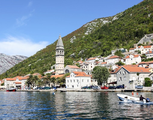 Perast town waterfront with bell tower and boat on the Bay of Kotor.