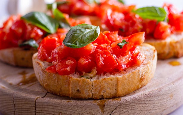 Bruschetta with fresh tomatoes and basil served on a wooden board during a Tuscan lunch.