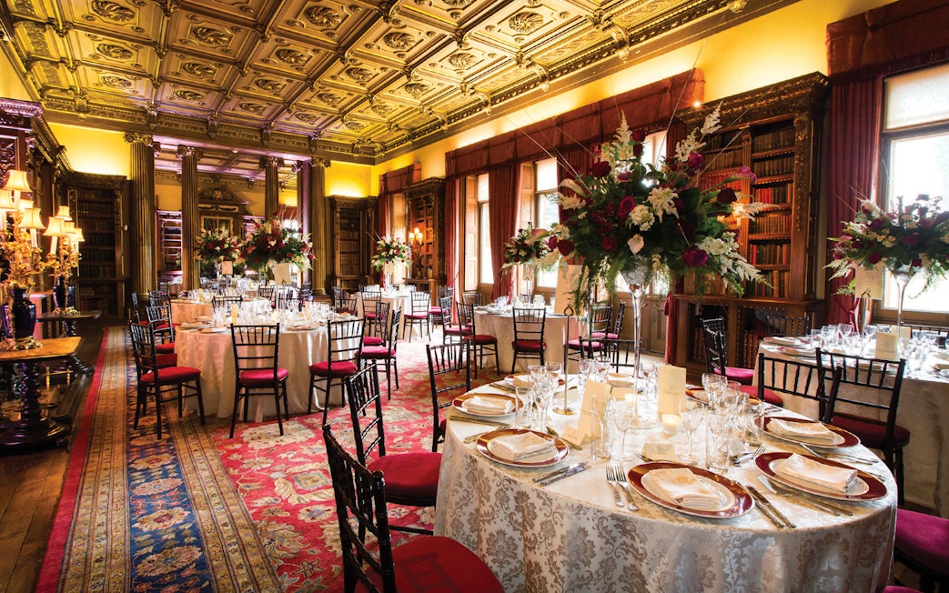 Elegant dining room setup at Downton Abbey with ornate ceiling and floral centerpieces.