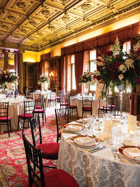 Elegant dining room setup at Downton Abbey with ornate ceiling and floral centerpieces.