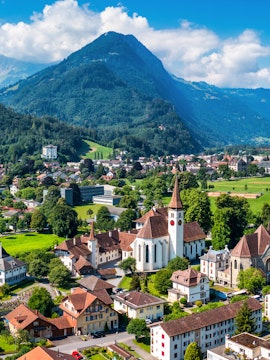 Aerial view of Interlaken, Switzerland, featuring a church and surrounding buildings with mountains in the background.