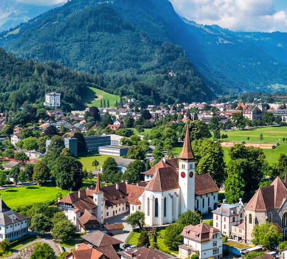 Aerial view of Interlaken, Switzerland, featuring a church and surrounding buildings with mountains in the background.