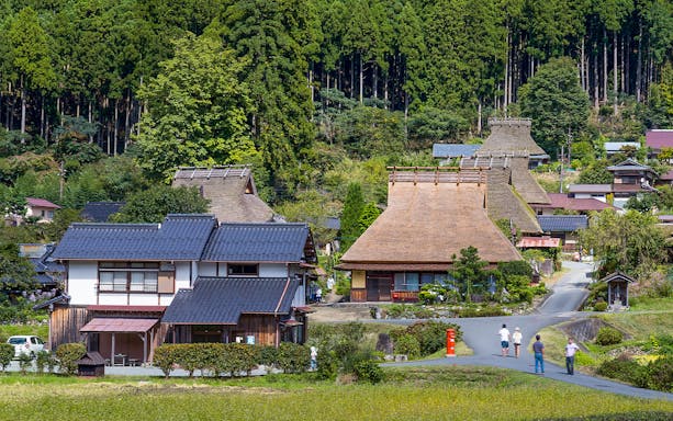 Traditional thatched-roof houses in Miyama Kayabuki No Sato, Kyoto, surrounded by lush greenery.