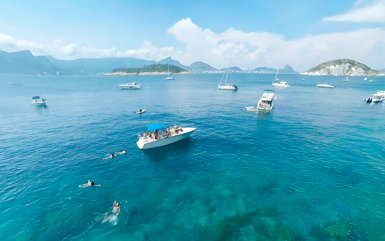 Boat cruising in Rio de Janeiro with swimmers nearby during a scenic tour.