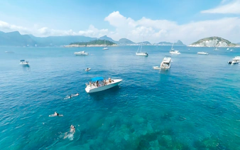 Boat cruising in Rio de Janeiro with swimmers nearby during a scenic tour.