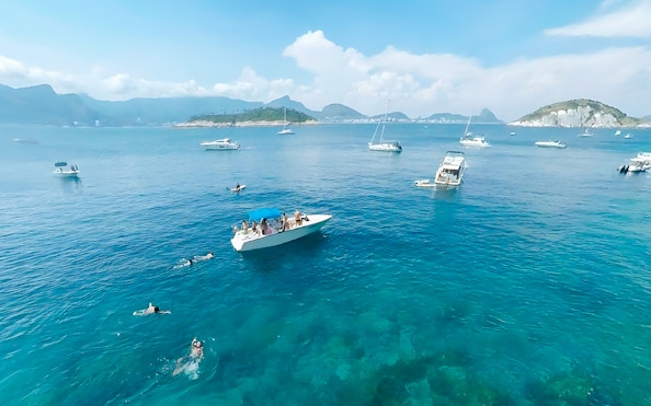 Boat cruising in Rio de Janeiro with swimmers nearby during a scenic tour.