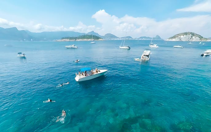 Boat cruising in Rio de Janeiro with swimmers nearby during a scenic tour.