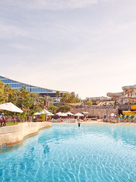 Visitors enjoying water rides at Wild Wadi Water Park, Dubai, with Jumeirah Beach Hotel in the background.