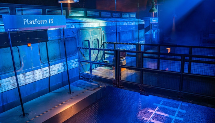 Platform 13 at Thorpe Park with train and tracks in dim lighting.