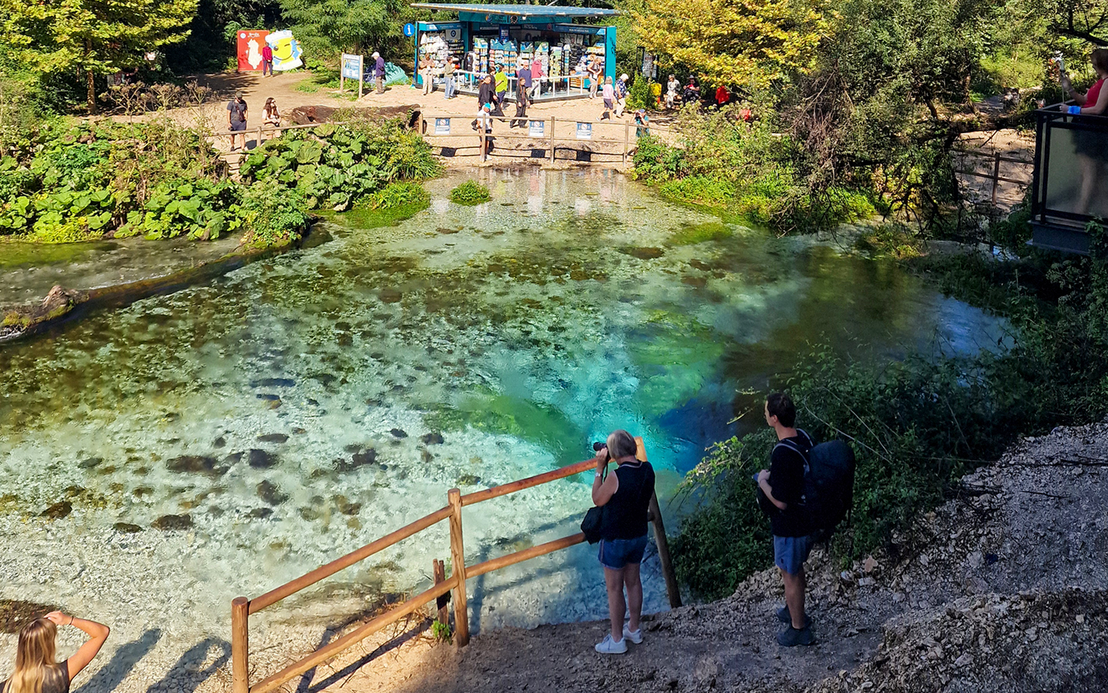 Visitors observing the Blue Eye spring in Albania with vibrant turquoise water.