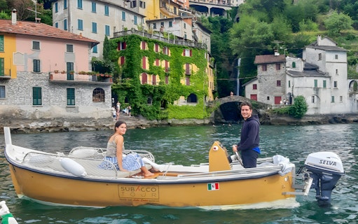 Boat rental on Lake Como with colorful lakeside buildings in the background.