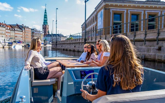 Guests on a boat tour in Copenhagen harbor, viewing city landmarks.