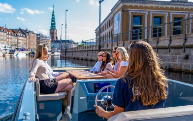 Guests on a boat tour in Copenhagen harbor, viewing city landmarks.