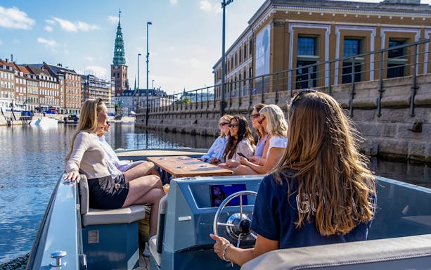 Guests on a boat tour in Copenhagen harbor, viewing city landmarks.