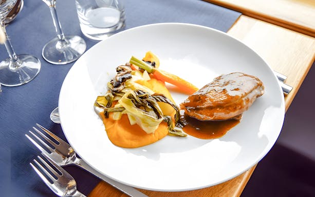 Plate of gourmet lunch served on Bateaux Bordelais cruise, featuring meat and vegetables.