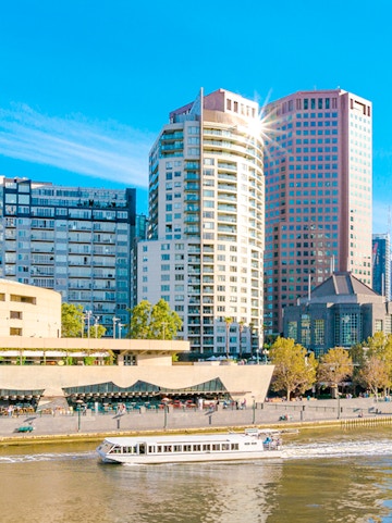 Cruise boat on Yarra River with Melbourne city skyline in the background.