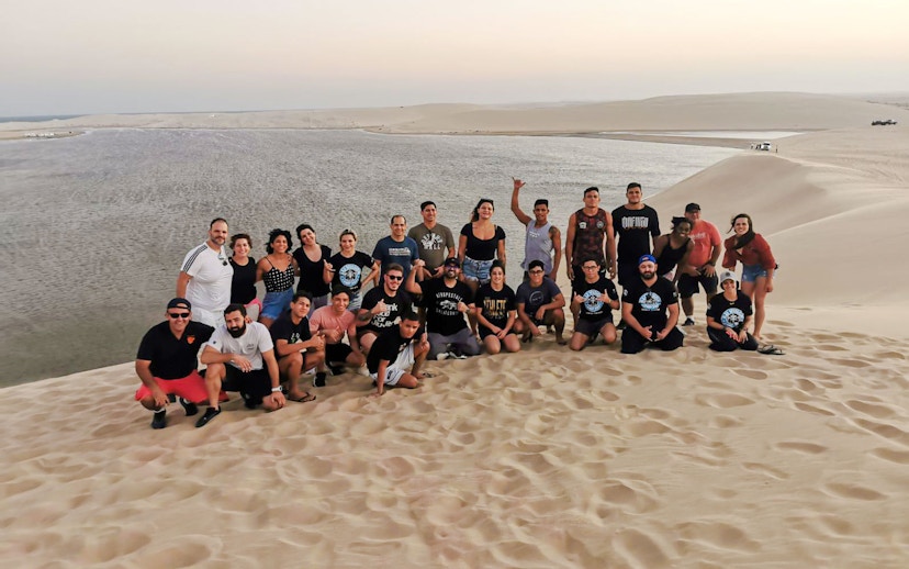 Group enjoying a desert safari in Doha with sand dunes and water in the background.