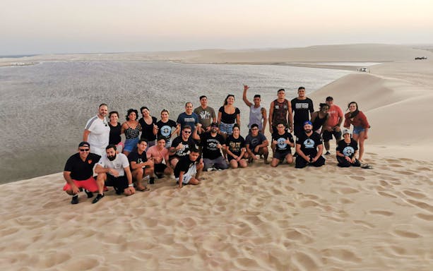 Group enjoying a desert safari in Doha with sand dunes and water in the background.