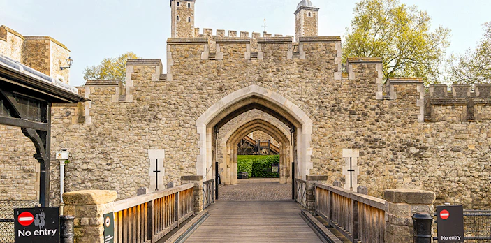 Tower of London stone entrance with arched gateway and surrounding walls.