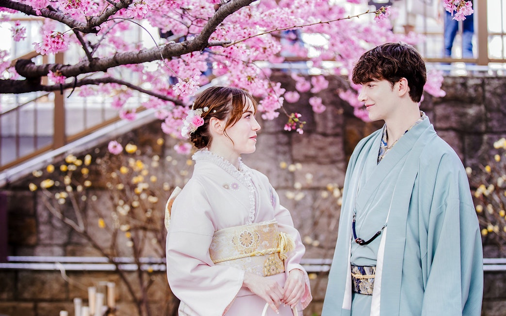 Couple in kimonos under cherry blossoms in Japan.