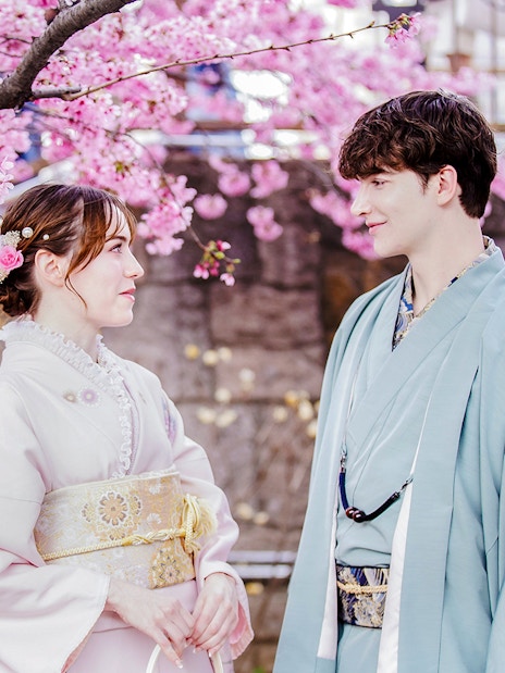 Couple in kimonos under cherry blossoms in Japan.