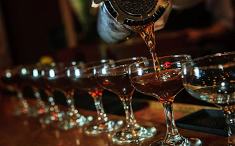 Pouring cocktails into glasses on a New Orleans craft cocktail walking tour.