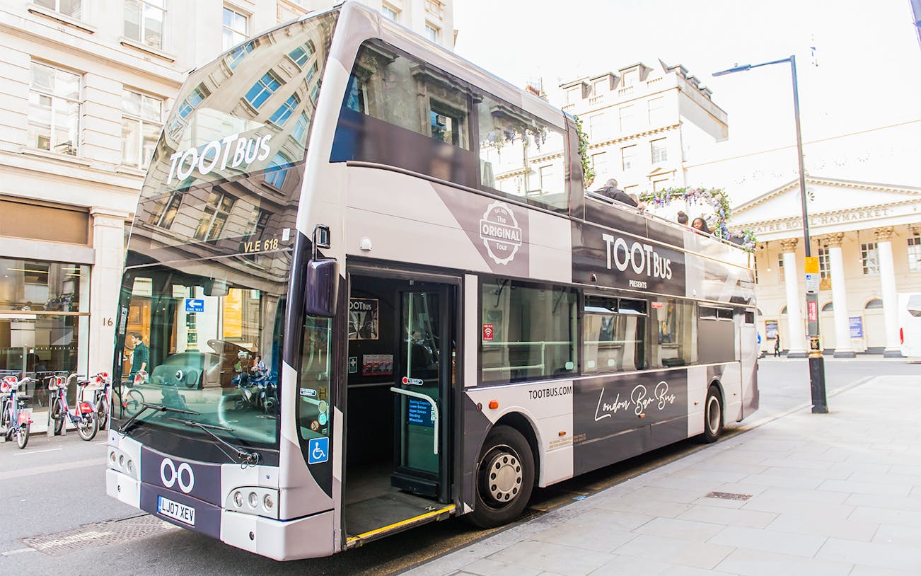Double-decker bus parked on a London street, offering a bar bus tour experience.
