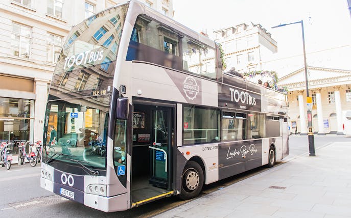 Double-decker bus parked on a London street, offering a bar bus tour experience.