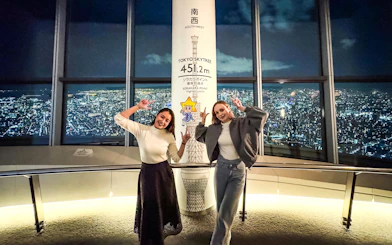 Visitors at Tokyo Skytree's observation deck with city view at night.