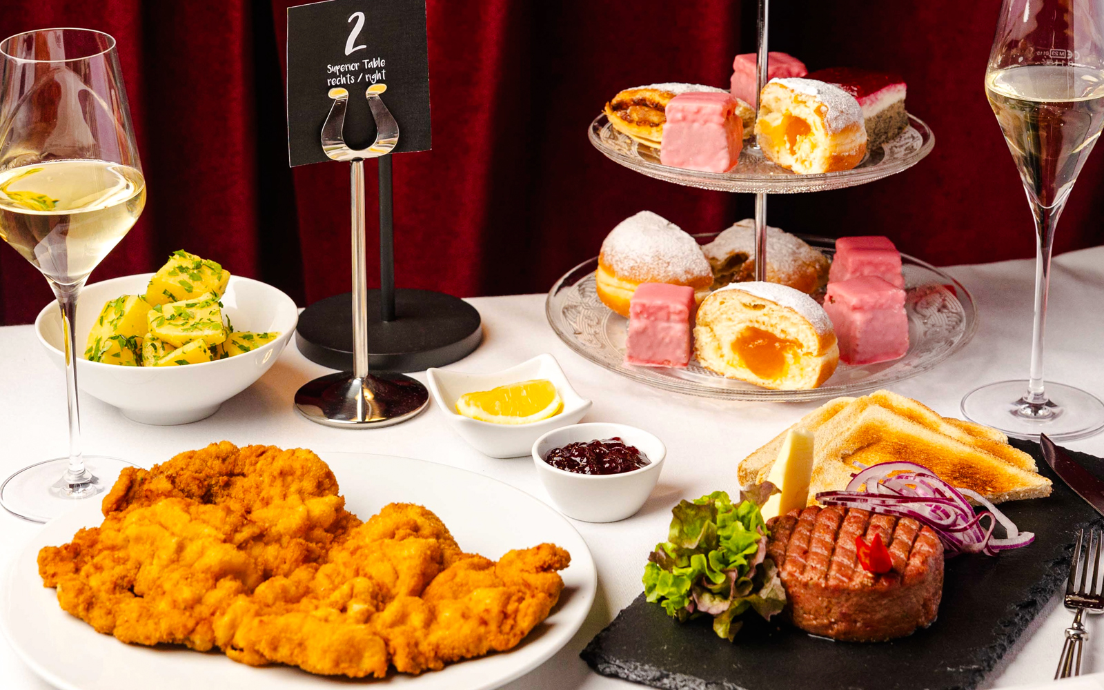 A gourmet dinner spread at Mirage in Vienna featuring schnitzel, steak tartare, and assorted desserts.