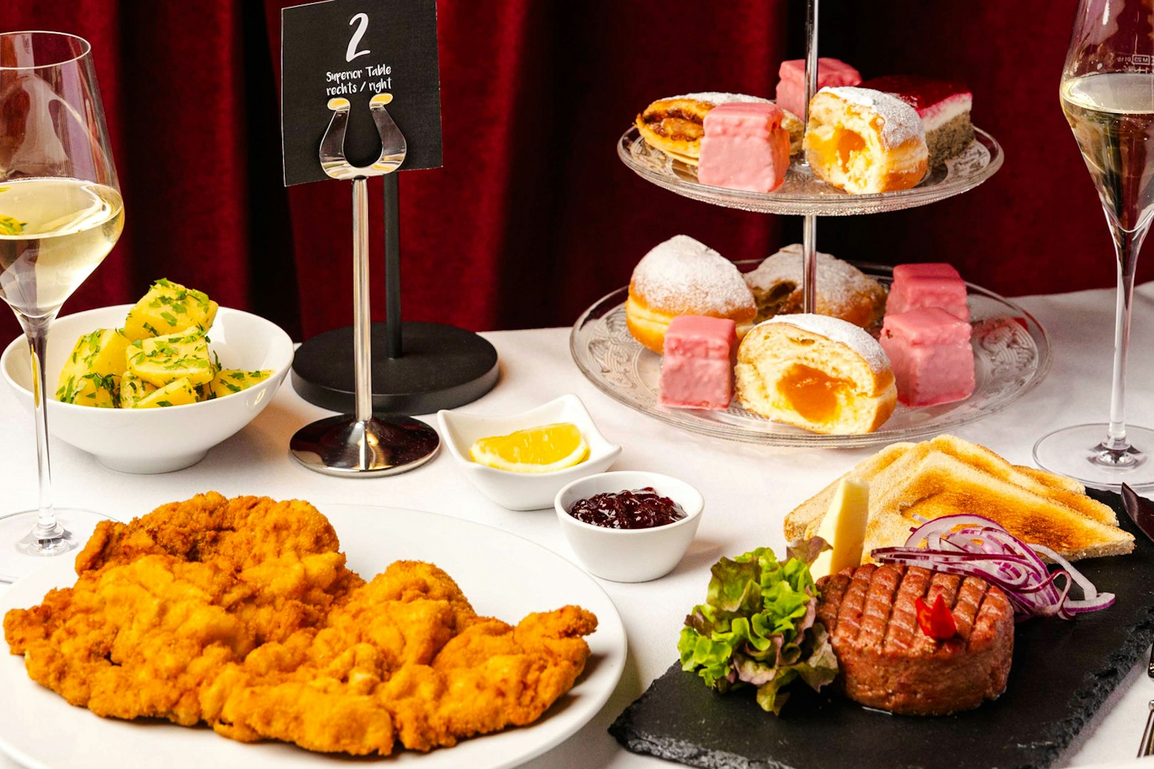 A gourmet dinner spread at Mirage in Vienna featuring schnitzel, steak tartare, and assorted desserts.