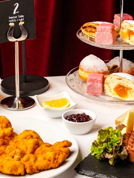 A gourmet dinner spread at Mirage in Vienna featuring schnitzel, steak tartare, and assorted desserts.