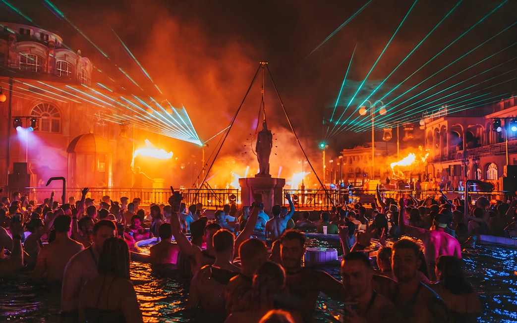 Crowd enjoying Sparty bath party with lights and music at Széchenyi Thermal Bath, Budapest.