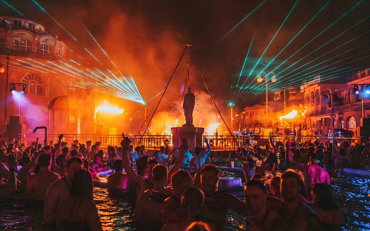 Crowd enjoying Sparty bath party with lights and music at Széchenyi Thermal Bath, Budapest.