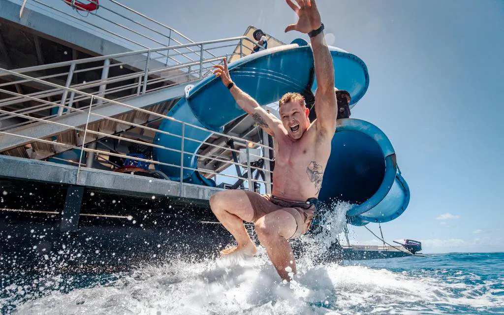 Man sliding into ocean from Sunlover Reef Cruises platform at Great Barrier Reef.