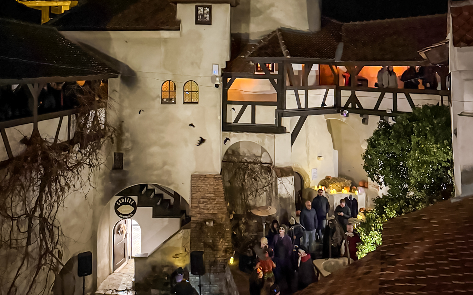 Bran Castle courtyard with Halloween decorations and visitors at night.