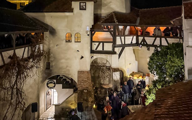 Bran Castle courtyard with Halloween decorations and visitors at night.