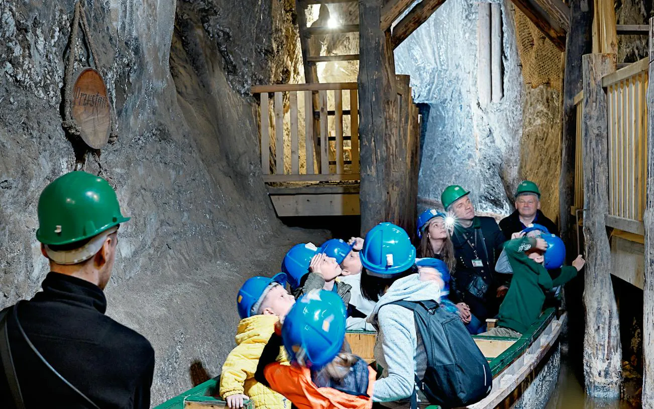 Visitors on a boat tour inside Bochnia Salt Mine, wearing helmets, Krakow.