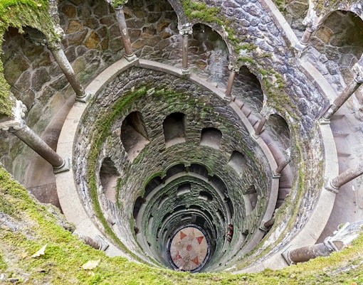 Tour guide leading a group through the lush gardens of Quinta da Regaleira in Sintra, Portugal
