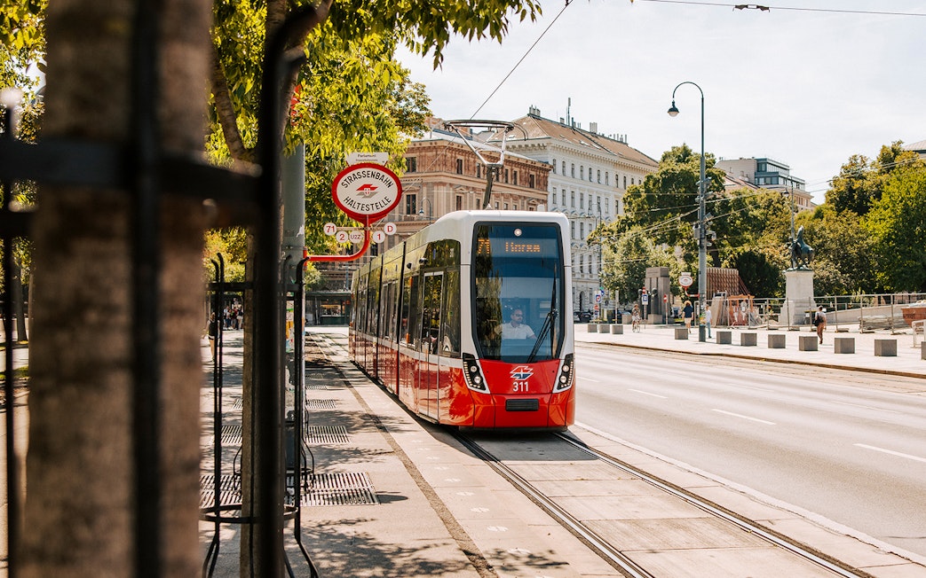 Tram on Vienna street near historic buildings, part of Vienna City Card benefits.