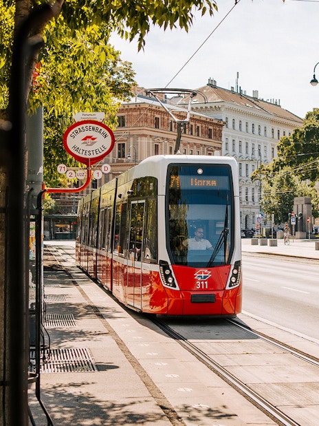 Tram on Vienna street near historic buildings, part of Vienna City Card benefits.