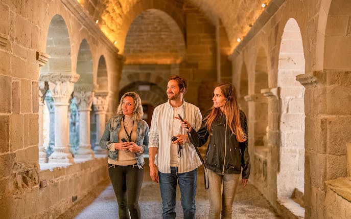 Visitors exploring the medieval cloister at Món Sant Benet.