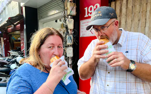 Tourists enjoying bánh mì on a street in Saigon, Ho Chi Minh City.