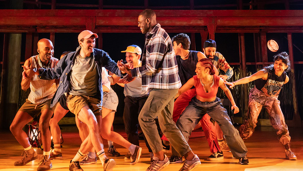 Group of performers dancing energetically on stage during an Illinoise show.