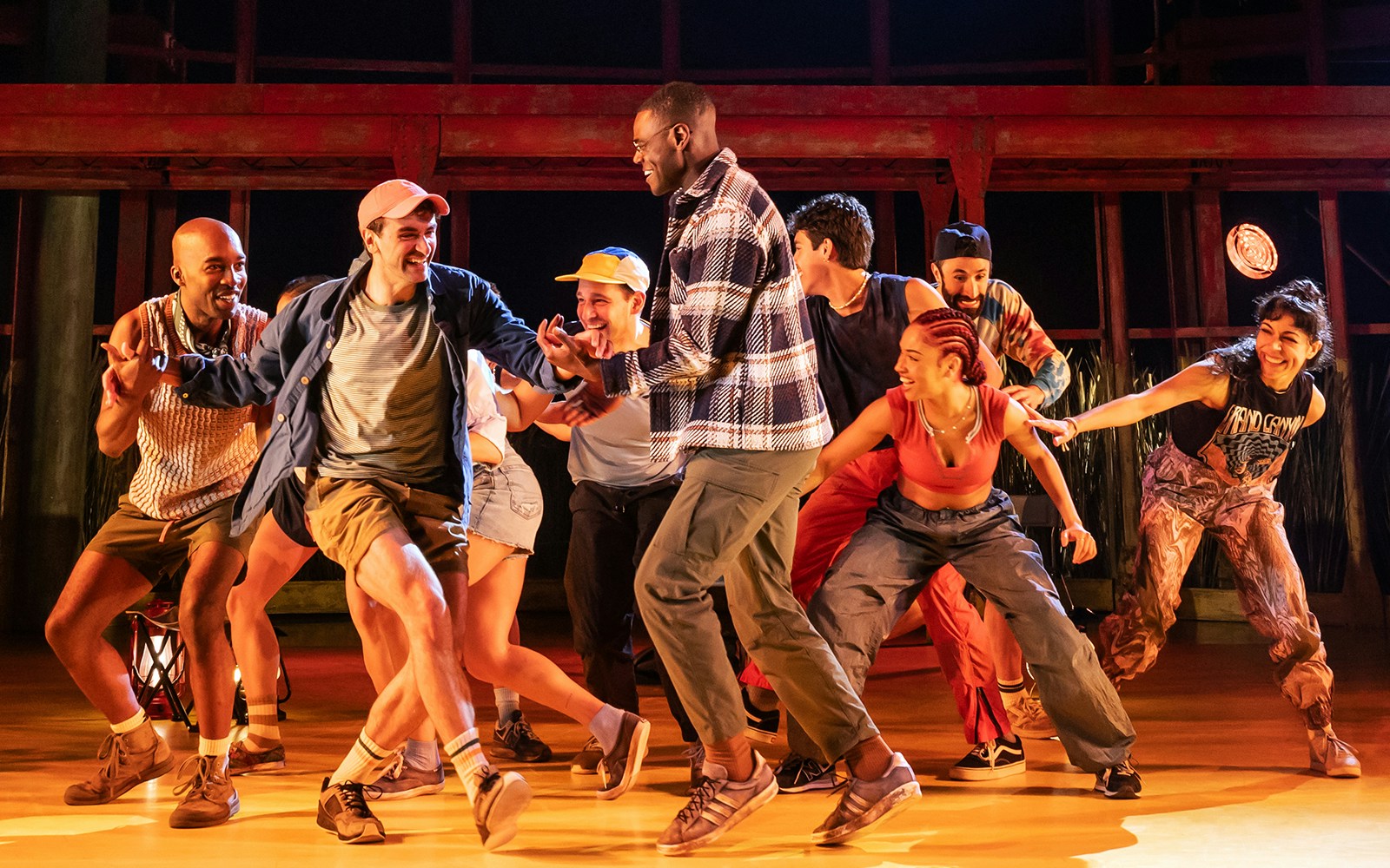Group of performers dancing energetically on stage during an Illinoise show.