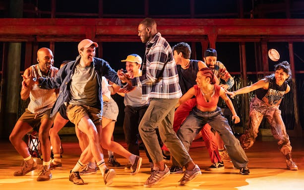Group of performers dancing energetically on stage during an Illinoise show.