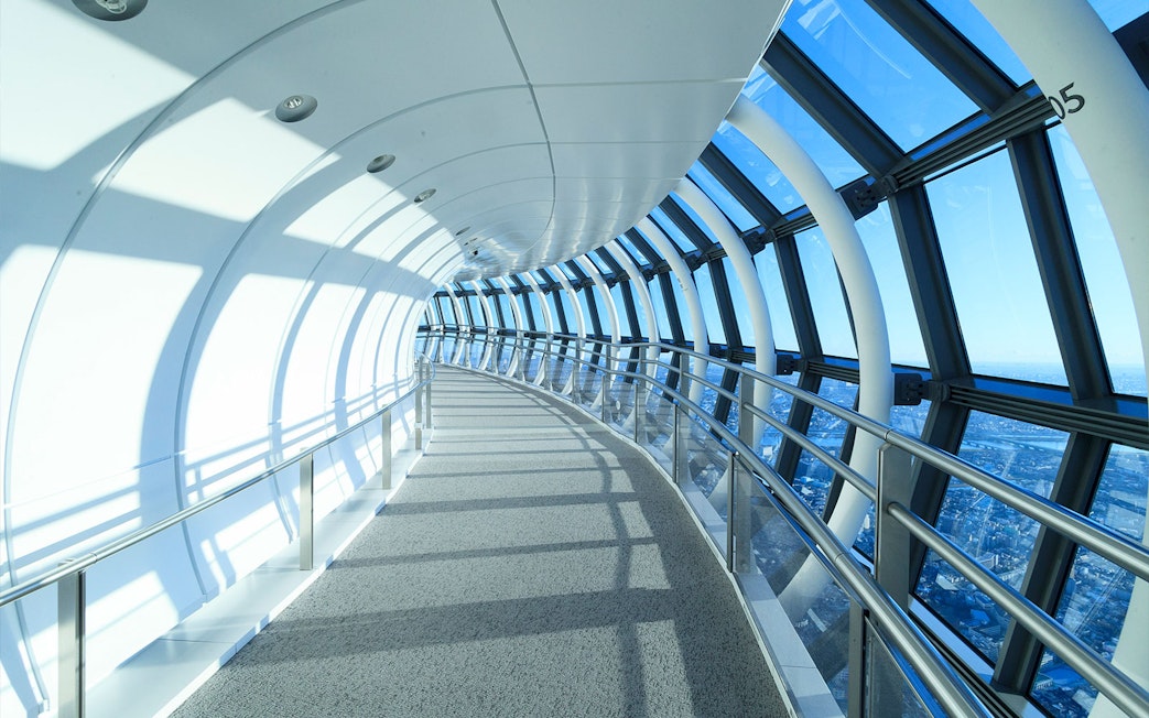 Curved glass corridor at SkyTree Observation Deck, Tokyo, with city view.