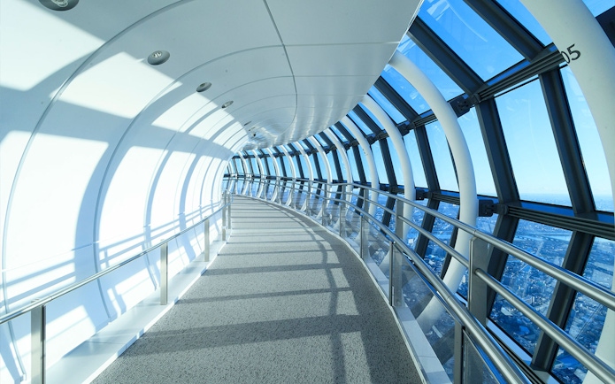 Curved glass corridor at SkyTree Observation Deck, Tokyo, with city view.