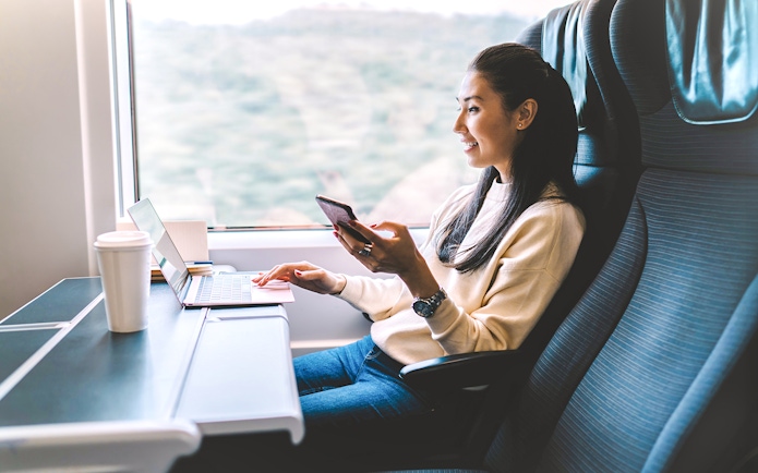 Young woman using smartphone on Eurostar train journey.