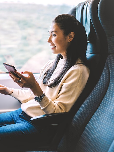 Young woman using smartphone on Eurostar train journey.